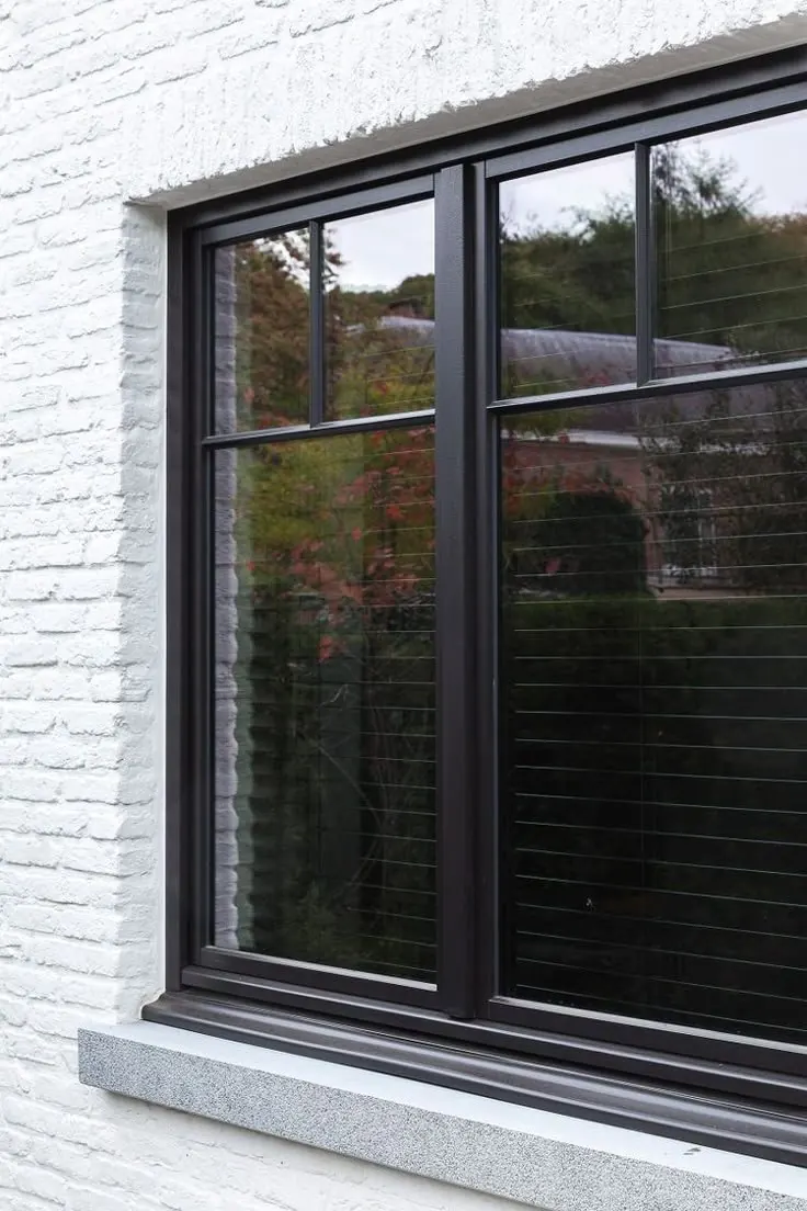 Fenêtre en PVC noir sur façade en brique blanche